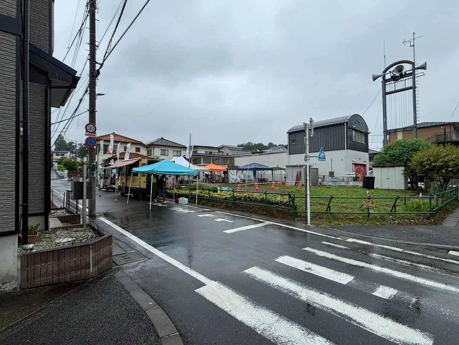 雨に濡れた道路と設営中の夕涼み会会場